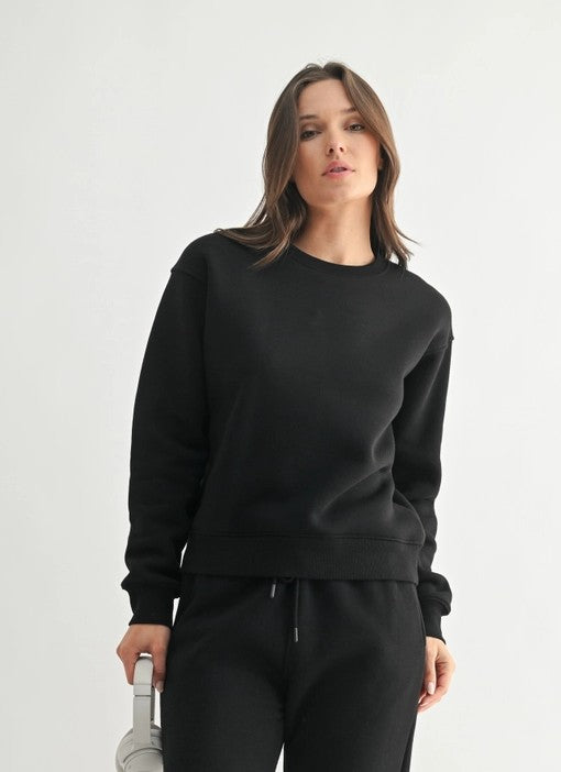 Woman wearing a black sweatshirt and pants on a white background