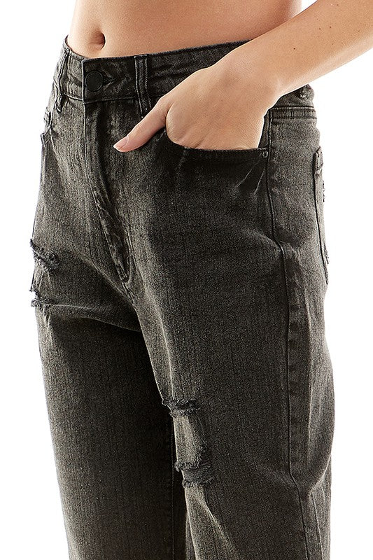 A female model wearing a white tank top and black distressed cuffed mom jeans with a zipper closure at RIODECA.