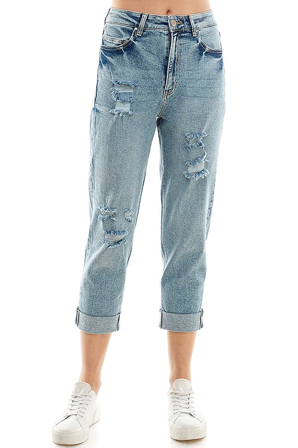 A female model wearing a white tank top and blue distressed cuffed mom jeans, paired with white sneakers.
