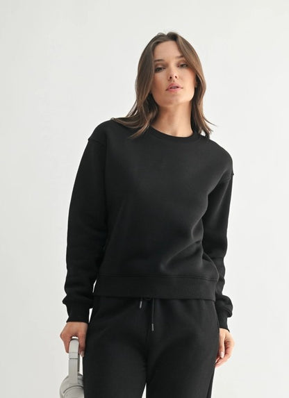 Woman wearing a black sweatshirt and pants on a white background
